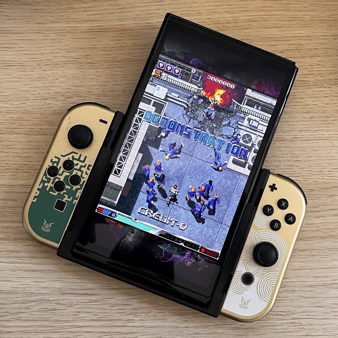 Eine Oled Switch mit Flip Grip zum vertikalen Spielen. Es läuft der Demonstrationsmodus von ESP Ra. De. Psi.