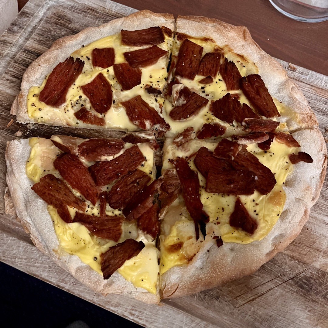 Eine Pizza mit Steak-Streifen und Sauce Hollandaise.