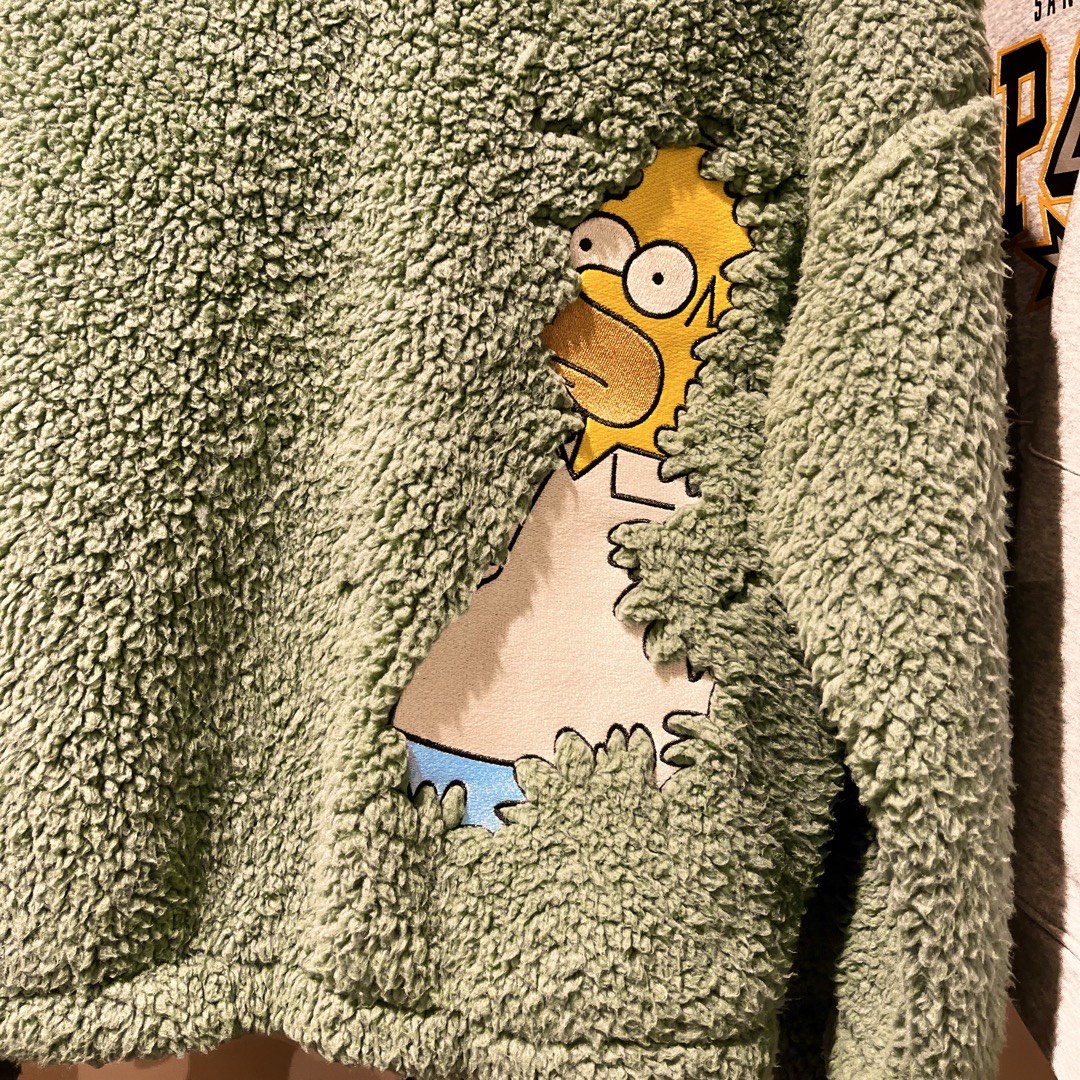 Ein Kinderpulli mit Homer Simpson, der rückwärts im flauschigen Stoff des Kleidungsstücks verschwindet.