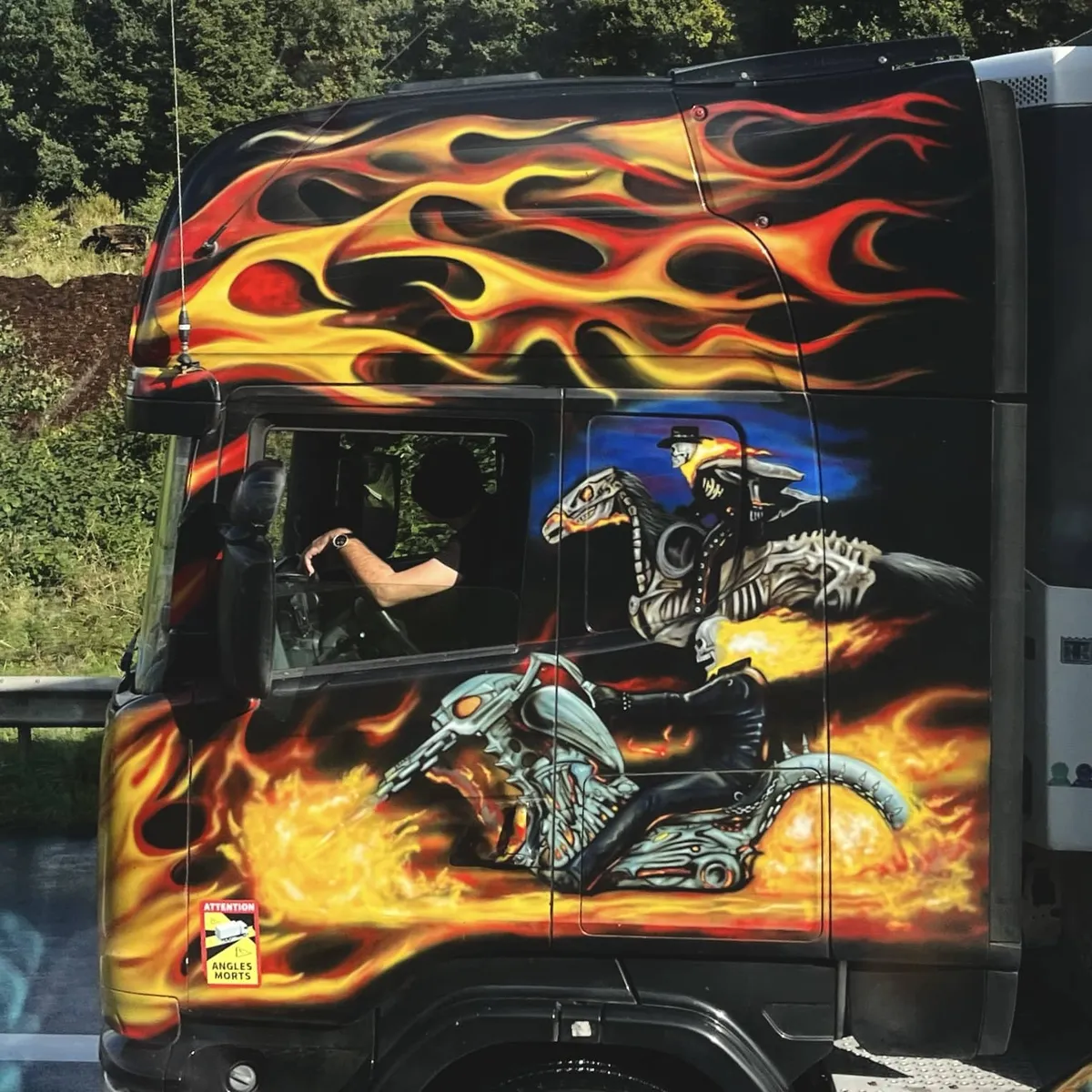 Eine Zugmaschine, komplett mit Airbrush bemalt. Den schwarzen LKW zieren Flammen und zwei Ghost Rider. Einer zu Pferd und einer auf dem Motorrad.